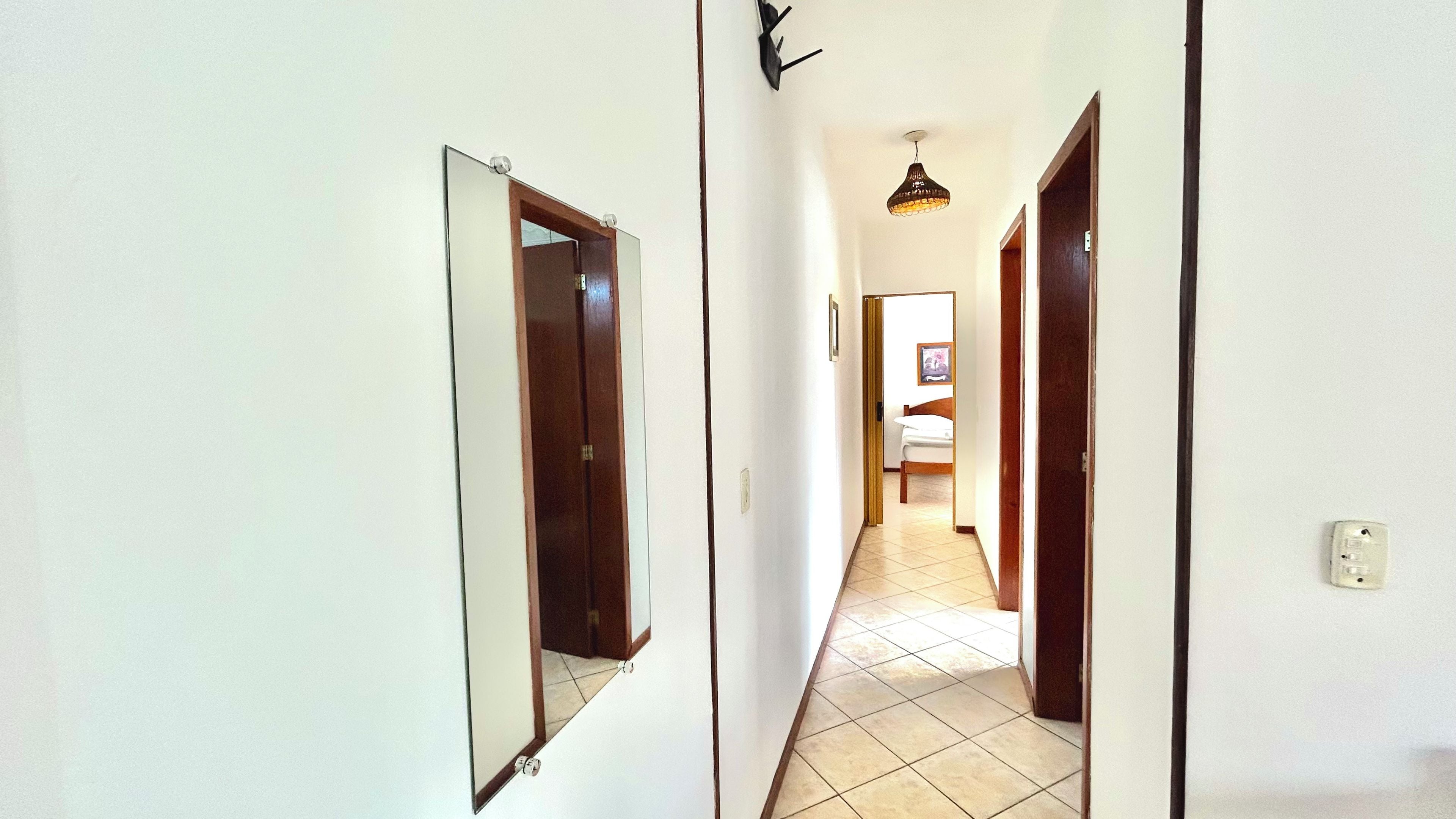 Un couloir avec deux portes, un luminaire et un lit au fond.