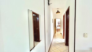A hallway with two doors, a light fixture, and a bed in the distance.