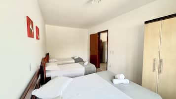 Habitación de hotel con dos camas individuales, un armario y una puerta que da a otra habitación.