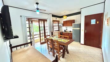 A dining area with a table and chairs, a ceiling fan, and a kitchen with cabinets and appliances.
