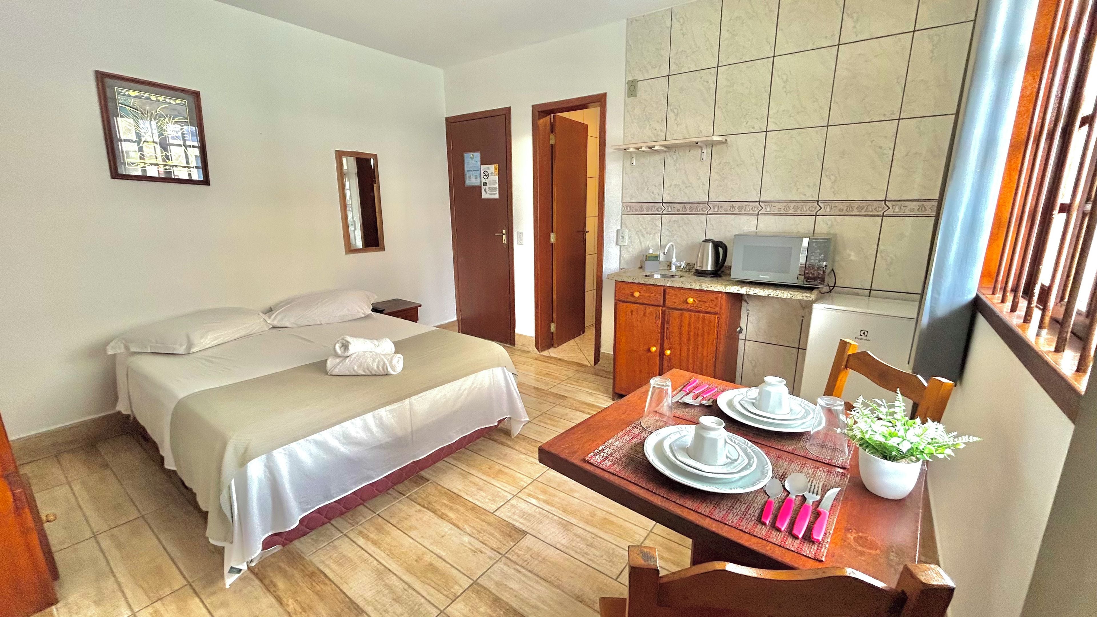 A hotel room with a bed, a dining table set with plates, a microwave, and a small kitchen area.