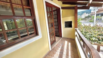 Un balcón con vistas a una calle y edificios, una puerta de madera y un ventanal con una placa.