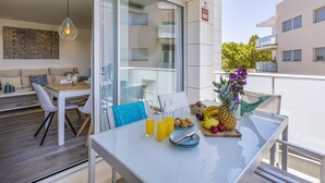 A balcony with a dining table set with breakfast, a glass wall, and a hanging light fixture.
