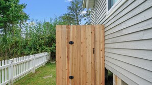 A wooden structure with two black handles, adjacent to a white fence and a house with siding.