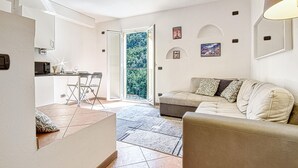 A modern living room with a sofa, a dining area with a table and chairs, and a balcony with a view of trees. - 1 bedroom pet friendly home in Avegno (Avegno)
