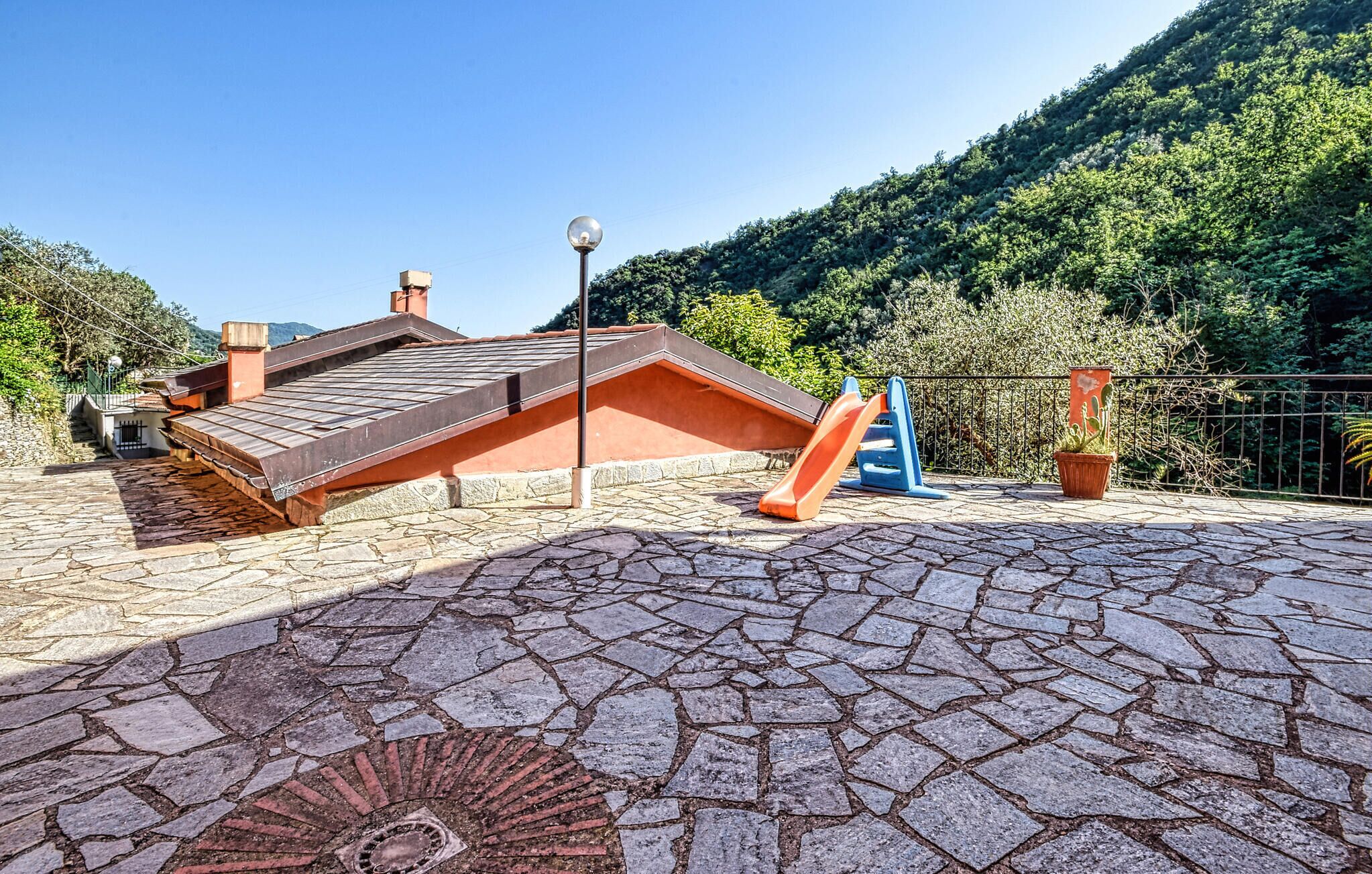 A paved area with a metal roof structure, a playground slide, and a potted plant. - 1 bedroom pet friendly home in Avegno (Avegno)