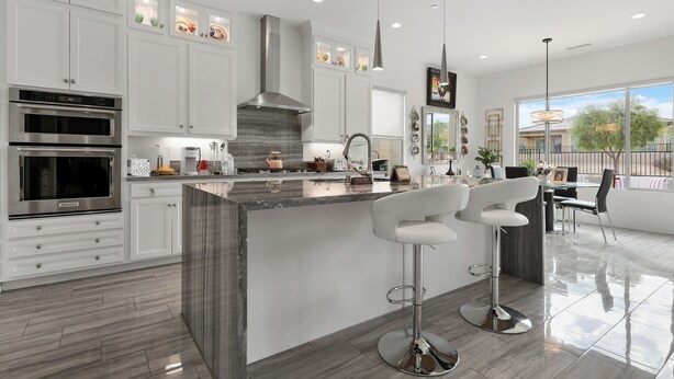 A modern kitchen with white cabinetry, stainless steel appliances, and a marble island with bar stools. - 2-bedroom house in superb Rancho Mirage Dell Webb 55+ Community. (Rancho Mirage)