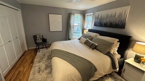A bedroom with a large bed, a nightstand with a lamp, a chair, and a window with curtains. - Fantastic mountain village condo in Steamboat Springs! Minutes to ski area base! (Steamboat Springs)