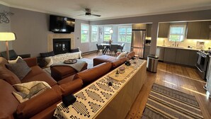 A modern living room with a brown sectional sofa, a fireplace, and a kitchen area with stainless steel appliances. - Fantastic mountain village condo in Steamboat Springs! Minutes to ski area base! (Steamboat Springs)