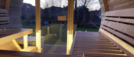 Una estructura de madera arqueada con bancos y una puerta de cristal que da al exterior.