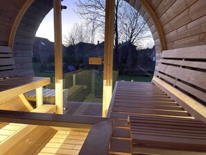 An arched wooden structure with benches and a glass door leading outside. - Framheim - 100qm Luxus-ferienhaus für 7 Personen Direkt am Wasser bei Greetsiel! (Krummhörn)