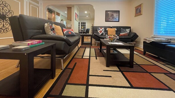 A living room with a black leather sofa, a coffee table, and a rug. - Charming 2-bedroom 1 bath, Livingroom, full kitchen, WiFi & AC in Alpharetta.  (Alpharetta)