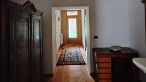 A hallway with wooden flooring, a patterned rug, a wooden cabinet, and a ceiling fan. - Apartment 'Appartamento Nide A Vodo' with Mountain View, Private Terrace and Balcony (Vodo di Cadore)