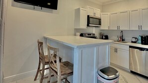 A modern kitchen with white cabinetry, a central island, a microwave, a stove, and a dishwasher. - Unit 7 -1 BDRM/Pool/Near Beach/Airport/Supermarket (Nassau)