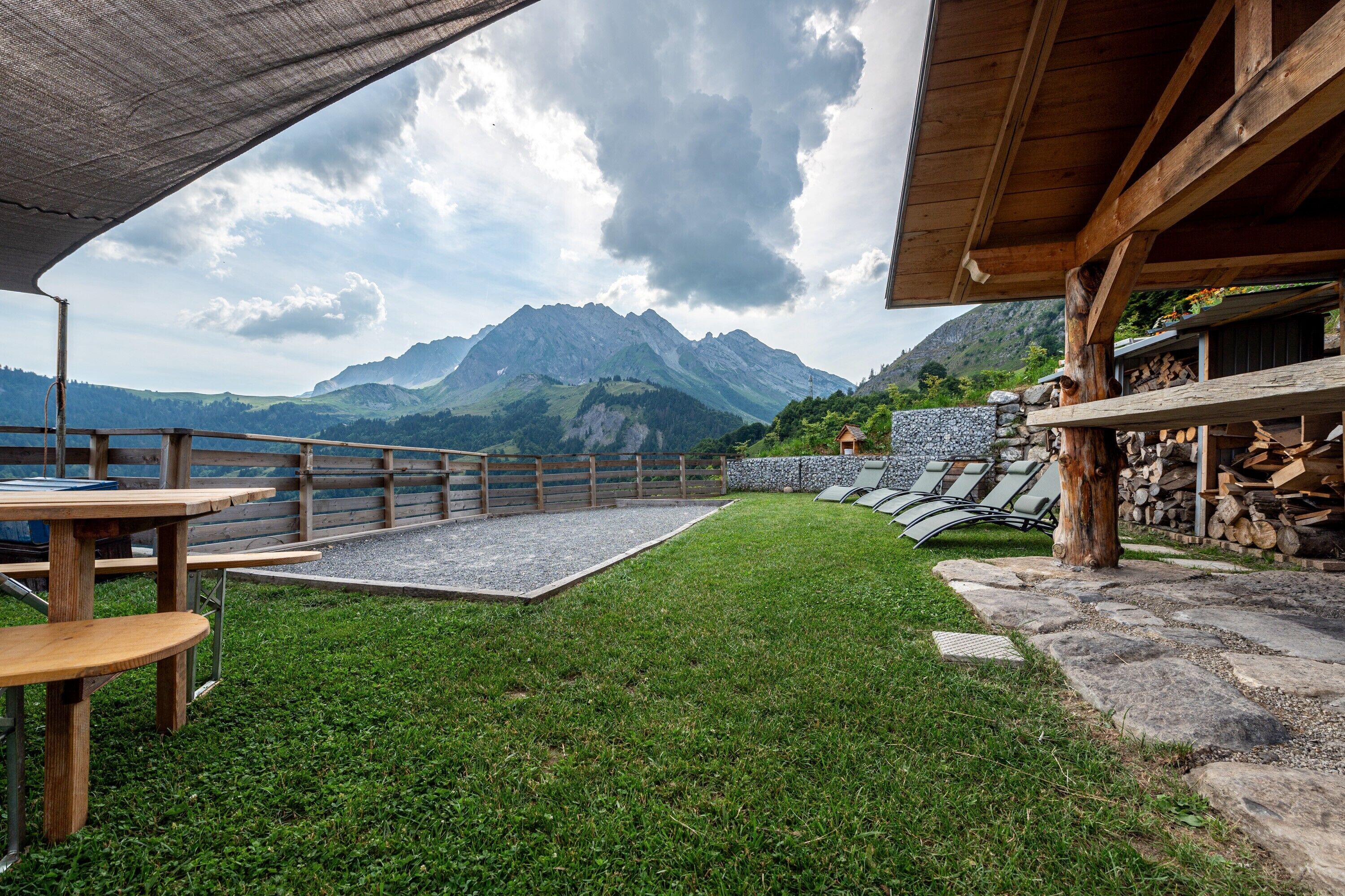 A patio with tables and chairs, a stone wall, and a mountain view.