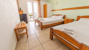 A hotel room with two wooden beds, a wooden bench, a wardrobe, and a view through a glass door. - Room 'Sea View - Aeolus Building' with Shared Pool, Shared Garden and Air Conditioning (Nikiana / Lefkas)