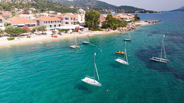 A coastal town with clear turquoise waters, boats, and buildings with red roofs.