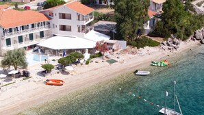 An aerial view of a coastal area with clear waters, a sandy beach, and a boat.