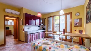 Habitación compacta con cama, pequeña cocina, zona de comedor y ventana.