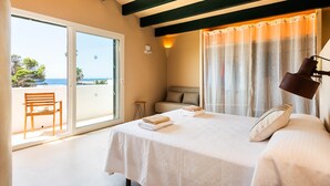 A bedroom with a bed, a chair, a small table, a window, and a view of the sea. - Villa 'Binimadi' with Sea View, Wi-Fi and Air Conditioning (Binisafua)