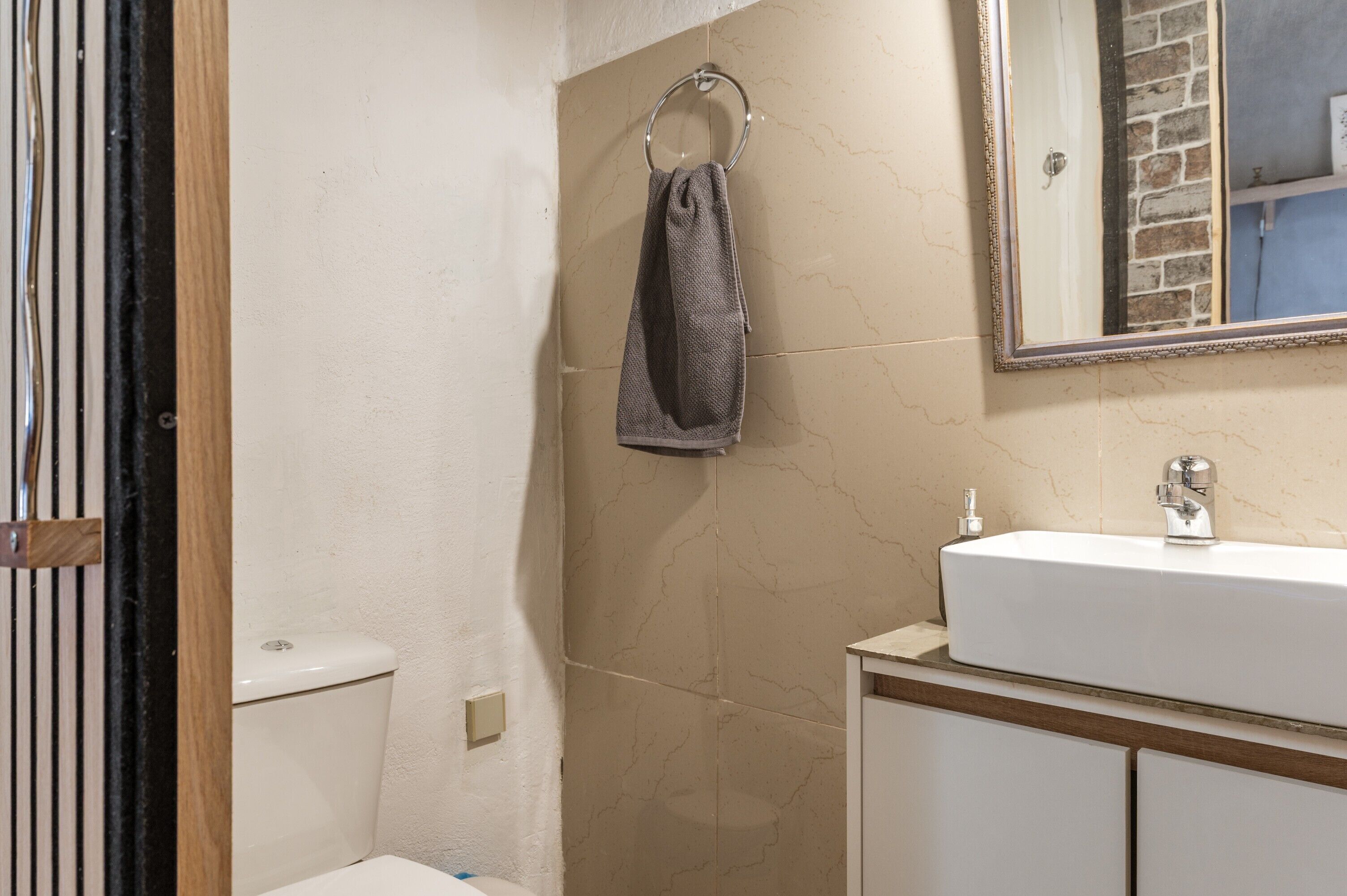 Une salle de bain équipée de toilettes, d’un lavabo, d’un miroir et d’un porte-serviettes.