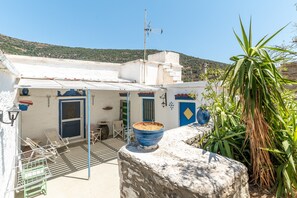 A rooftop terrace with a blue bowl, a door, and a chair.