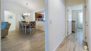 Eine moderne Wohnung mit Essbereich, Küche und einem Flur, der in einen weiteren Raum führt.