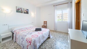 A bedroom with a bed, a chair, a desk, and artwork on the wall. - Room 'Doble 12' with Wi-Fi and Air Conditioning (Roquetas de Mar)