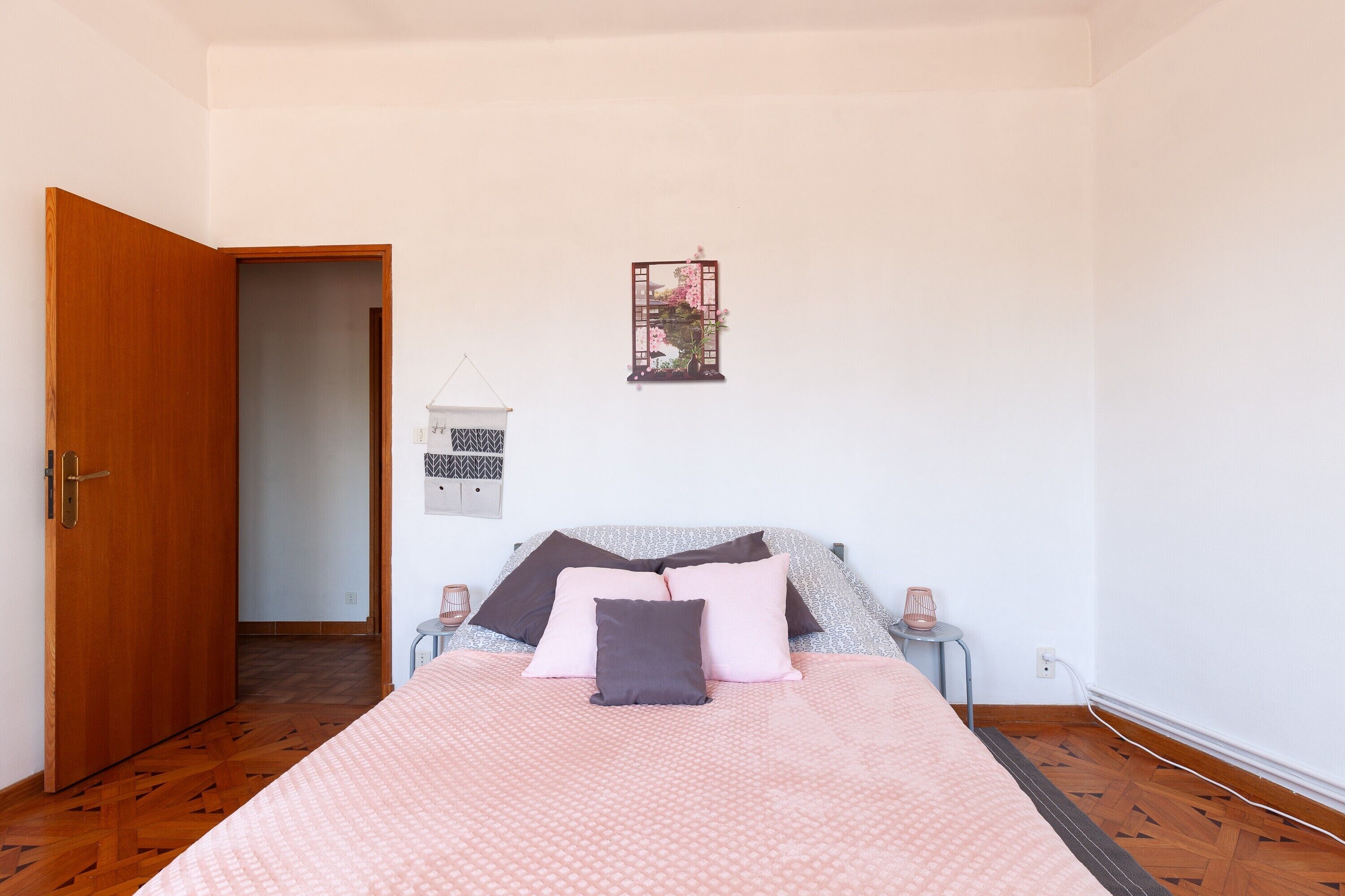 Une chambre à coucher avec un lit, des tables de chevet, un luminaire suspendu et une porte.