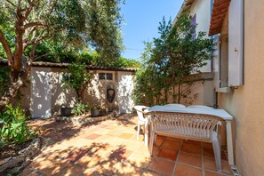 Una zona patio con tavolo e sedie, circondata da piante in vaso e un pavimento piastrellato.