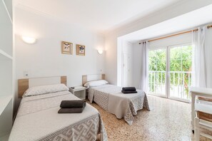 A hotel room with two beds, a nightstand, a window with curtains, and a view of greenery outside. - Room 'Doble Individual 11' with Wi-Fi and Air Conditioning (Roquetas de Mar)