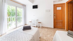 A bedroom with a bed, a desk, a TV, and a door.