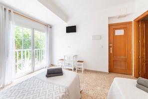Um quarto com uma cama, uma escrivaninha, uma televisão e uma porta.