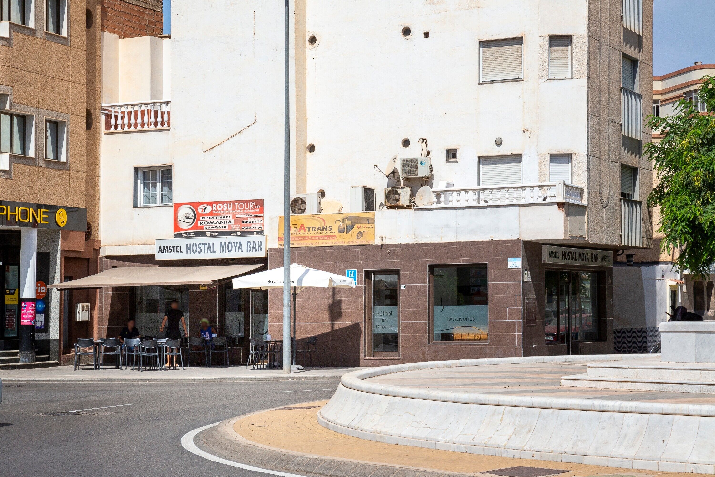 Un edificio con un cartel que dice 'AMSTEL HOSTAL MOMA BAR' y un letrero de 'TELÉFONO'.
