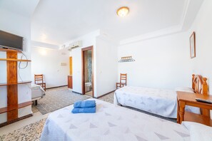 A hotel room with two beds, a TV, a desk, and a bathroom visible through an open door.