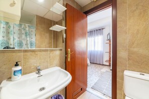 A bathroom with a sink, mirror, shower, and toilet.