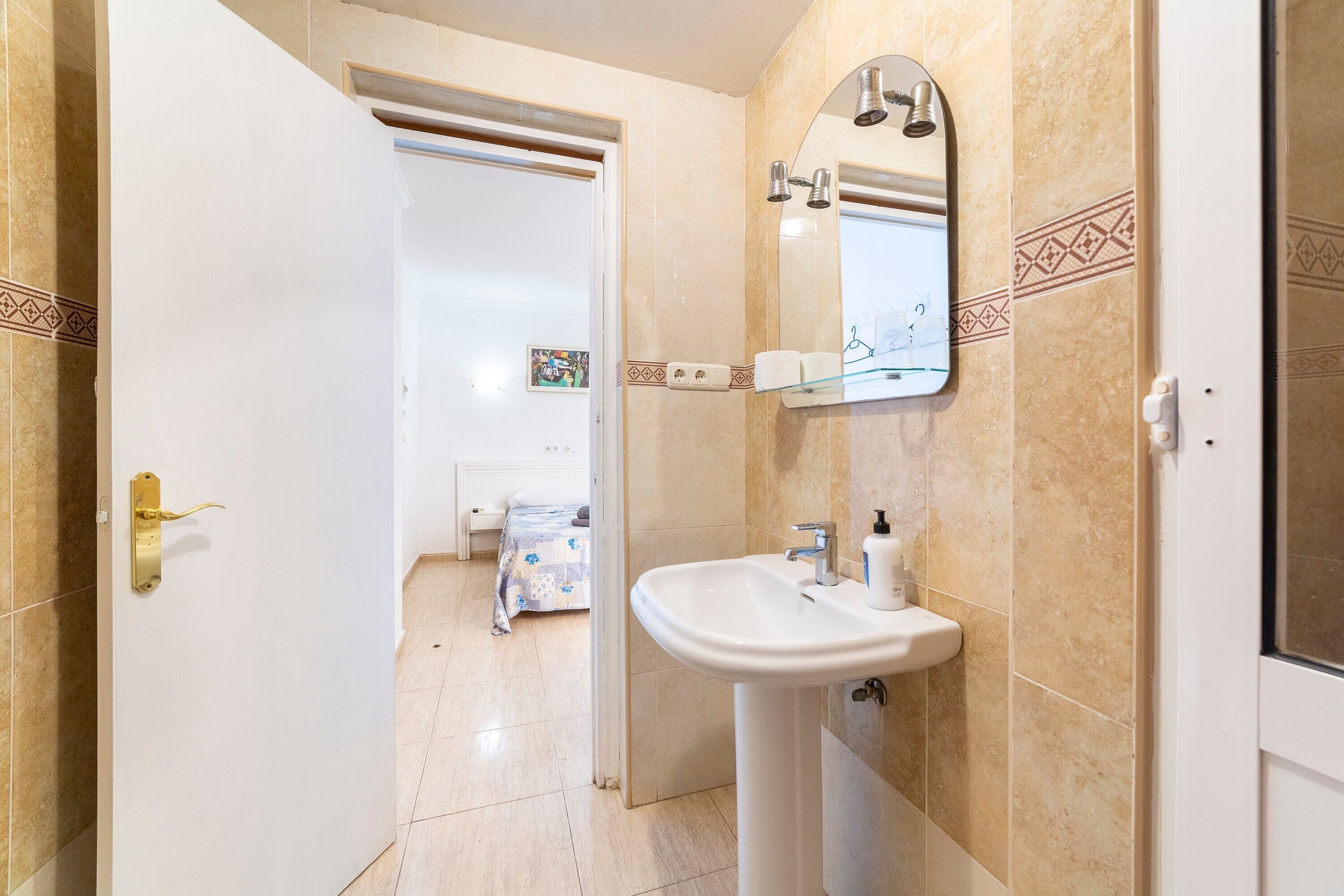 A bathroom with a sink, mirror, and shower.
