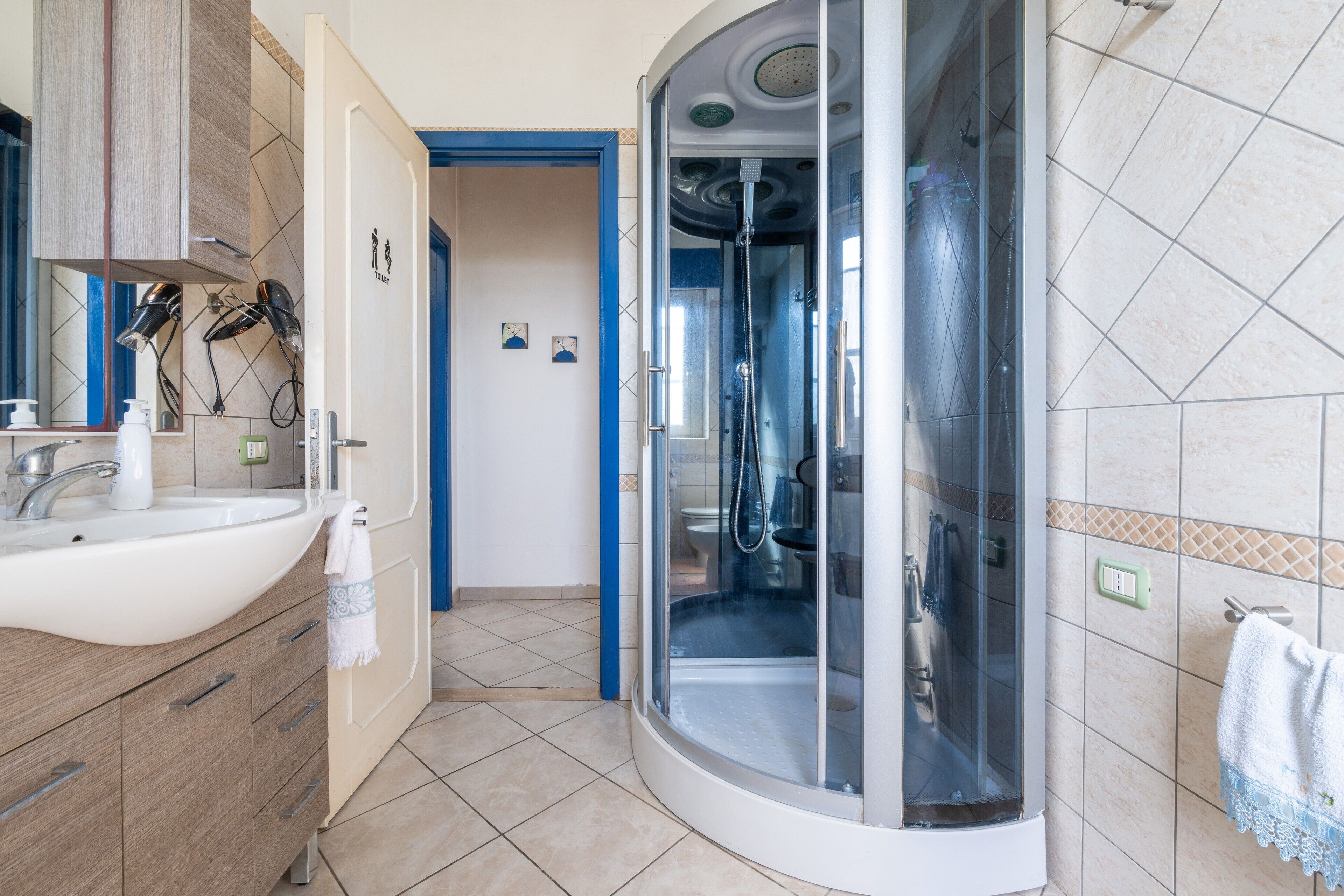 Une salle de bain équipée d’un lavabo, d’un miroir, d’un sèche-cheveux et d’une cabine de douche.