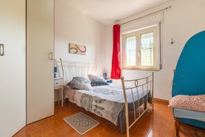 A bedroom with a bed, a window with curtains, a bedside table, and a chair. - Holiday Home 'La Casa Di Coccola' with Garden, Terrace & Wi-Fi (giba)