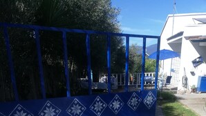 A blue gate with decorative patterns, a gravel path, and a building with a white exterior in the background.