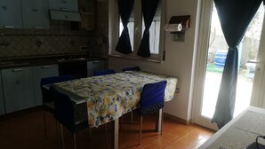 A compact kitchen with a dining table, chairs, and a window with curtains.