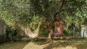 A hammock hanging from a tree in a garden with a bamboo fence in the background.