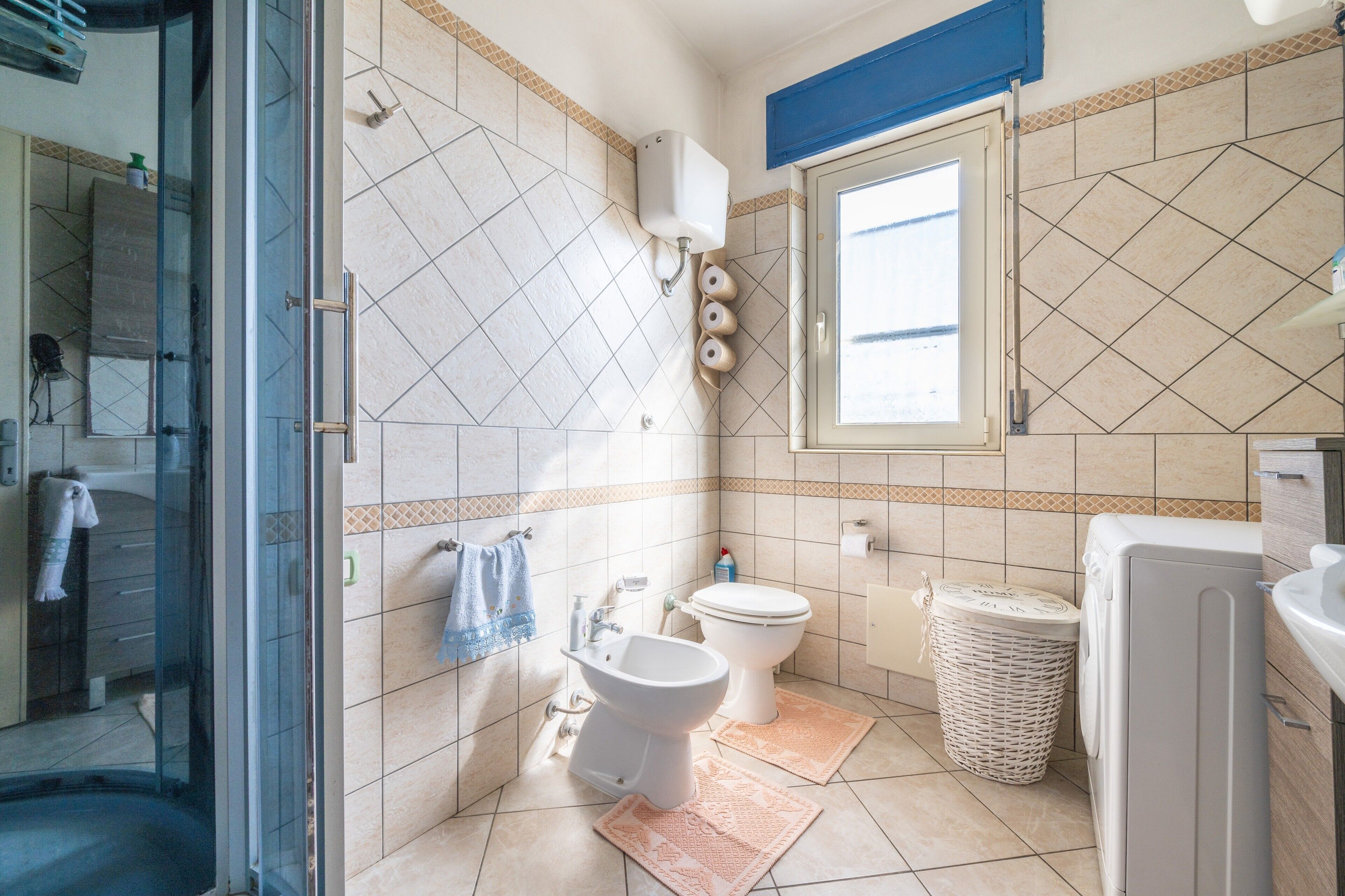 Une salle de bain équipée de toilettes, d’un bidet et d’une douche à parois de verre.