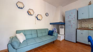 Un espace de vie compact comprenant un canapé, une kitchenette et une horloge murale.