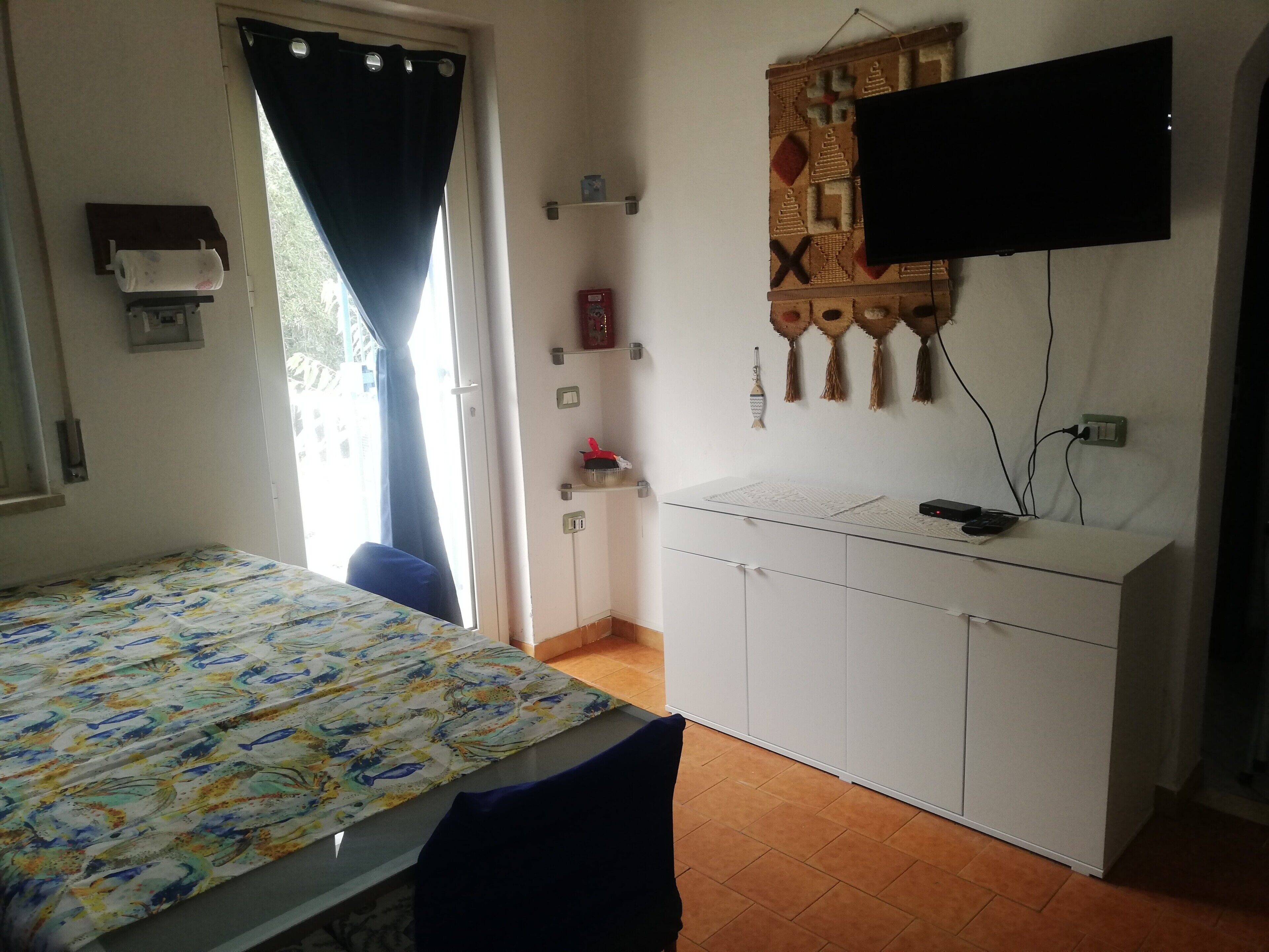 Une chambre à coucher avec un lit, un bureau, une télévision et une fenêtre avec des rideaux.
