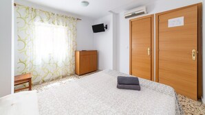 Una camera da letto con un letto, un'armadio in legno, un piccolo tavolo di legno e una TV a muro.