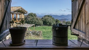 A rustic wooden structure with a view of mountains and a potted plant on a windowsill. - Apartment 'La Rústica' with Mountain View, Shared Garden and Wi-Fi (susqueda)