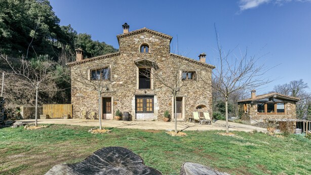 A stone building with a symmetrical facade, a central entrance, and a small annex to the right. - Apartment 'La Rústica' with Mountain View, Shared Garden and Wi-Fi (susqueda)
