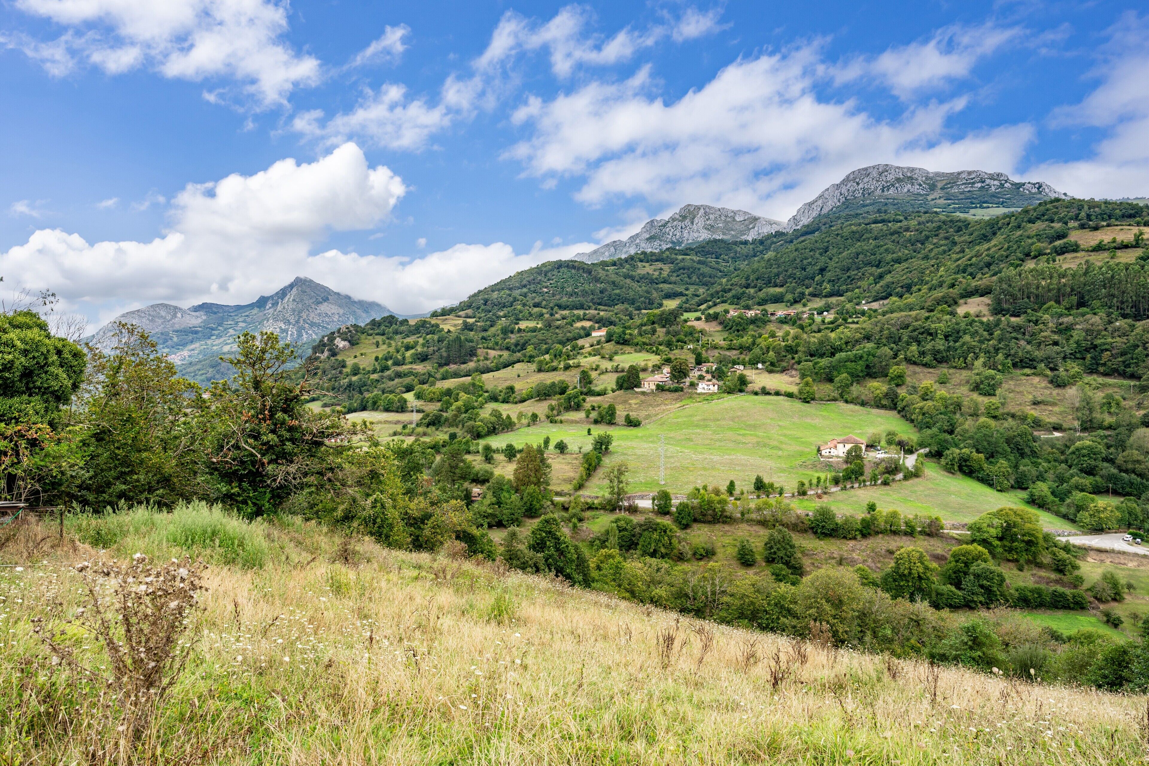 Paisagem montanhosa com uma pequena aldeia e casas.