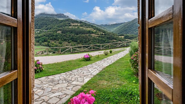 A stone pathway leading to a wooden fence overlooking a mountainous landscape.
